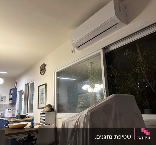 מזגן מותקן על קיר מעל חלון זכוכית